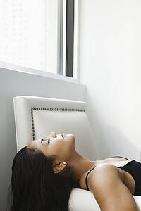 Profile of young adult woman lying on her back with eyes closed.