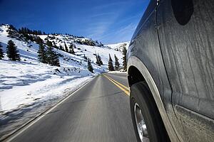 Perspective shot of SUV driving down road in snowy Colorado during winter.