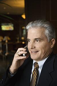 Adult male businessman talking on cell phone in hotel lobby.