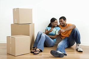 Couple sitting on floor next to moving boxes relaxing