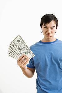 Young man holding money with disgust on his face