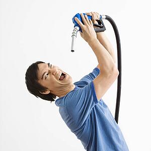 Young man fighting with gasoline pump nozzle