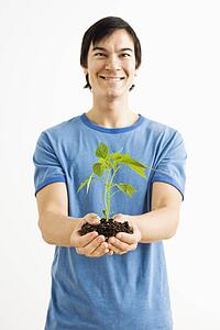 Man standing holding growing plant
