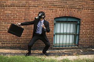 Businessman standing next to brick wall wearing gas mask in fighting stance