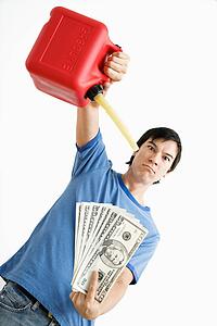 Man holding gas can pouring gasoline onto money