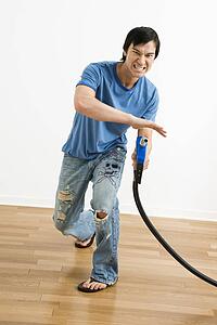 Young man aiming gasoline pump nozzle like a gun