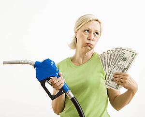 Woman holding gas nozzle and lots of money