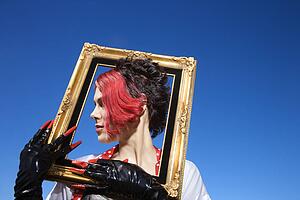 Young adult Caucasian female holding empty frame around head.