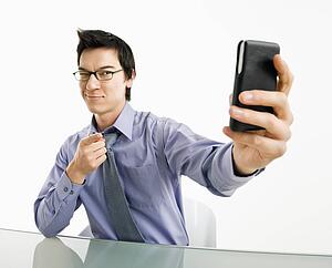 Businessman taking photograph of himself using pda or mobile phone device