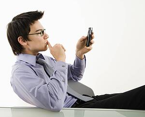 Businessman sitting at desk texting using his pda cellphone