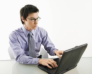 Businessman sitting at desk working on laptop computer