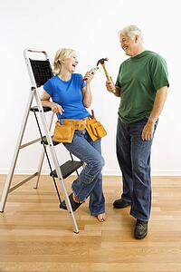 Couple with household tools next to ladder