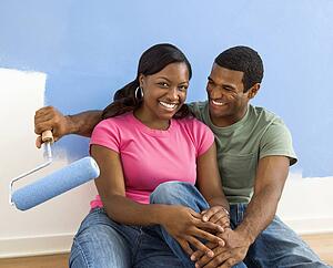 Couple relaxing together next to half-painted wall