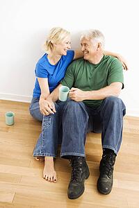 Couple sitting on floor snuggling and drinking coffee