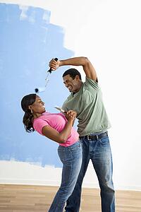 Young man pretending to paint woman's face with paint roller