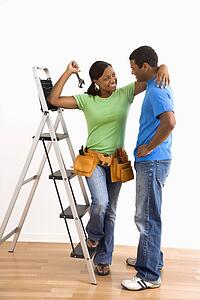 Portrait of smiling male and female couple with home repair tools and ladder