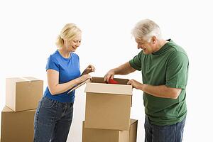 Mature couple packing or unpacking moving boxes