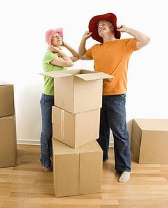 Couple trying on silly hats while packing or unpacking moving boxes
