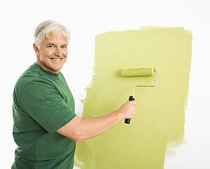Man painting wall green with paint roller