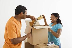 African American male and female couple packing cardboard boxes with shoes.