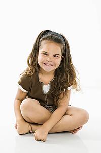 Cute little girl sitting looking at viewer smiling