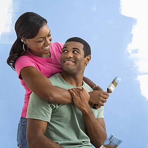 Portrait of male and female couple next to half-painted wall