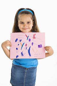 Smiling girl proudly holding drawing