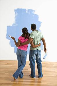 Couple standing together looking at half-painted wall