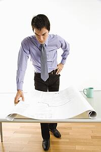Business man standing looking over blueprints