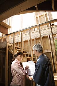 Male and female with blueprints on building construction site