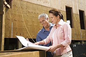 Male and female looking at blueprints in construction phase of house