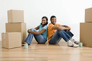 Male and female couple sitting on floor next to moving boxes