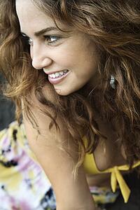Young adult Caucasian female smiling with hair blowing.