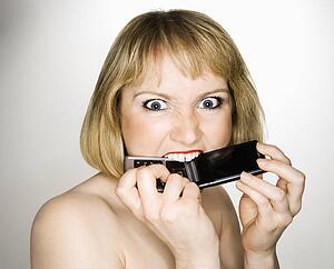 Woman who is biting her cellphone angrily