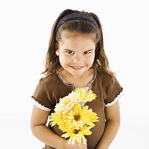 Young girl holding bouquet of yellow flowers.