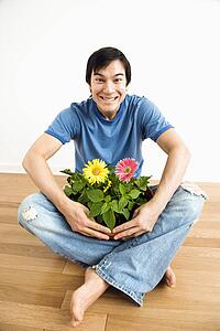 Man sitting holding pot of gerbera daisies.