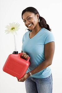 Young adult female holding gas can with flower in it's nozzle.