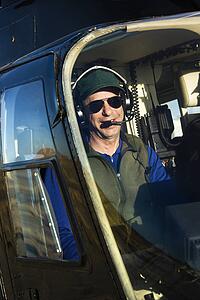 Portrait of helicopter pilot sitting in cockpit looking at viewer.