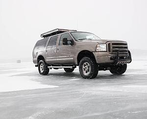 Four wheel drive truck with roof rack parked on desolate frozen lake