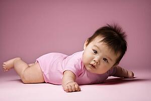Baby lying on stomach holding arms out to side