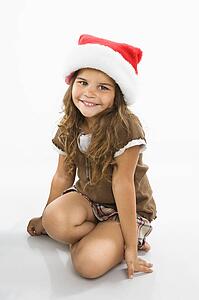 Girl sitting on floor wearing santa hat