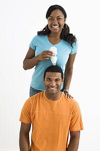Female holding energy-saving light bulb over man's head