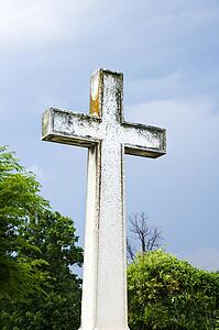 Cross in graveyard against blue sky and clouds