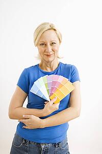 Portrait of smiling adult blonde woman holding paint swatches
