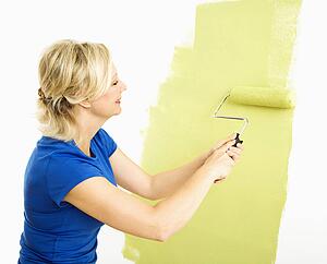Woman painting wall green with paint roller