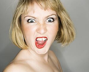 Portrait of young blonde caucasian woman who is looking at the viewer with angry expression.