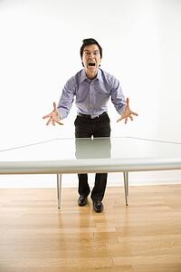 Business man standing at conference table yelling at unseen person