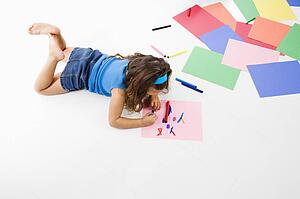 Girl coloring on construction paper