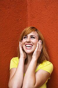 Smiling young redhead female with hands over ears