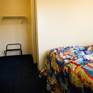 Interior shot of motel room with unmade bed and closet.
